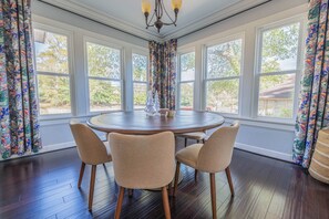 A dining area with a round table and four chairs, large windows, and a chandelier. - Stone Pool House - Sleeps 8 (Columbus)