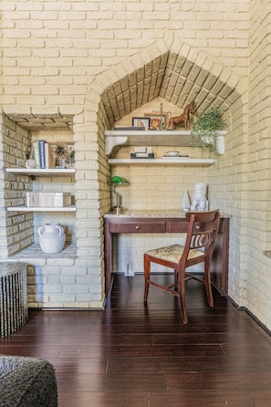 Un espace de travail comprenant un bureau, une chaise et des étagères où sont rangés des livres et des objets décoratifs.