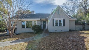 A single-story house with a gabled roof, a front entrance with a door, and a small porch area. - Stone Pool House - Sleeps 8 (Columbus)