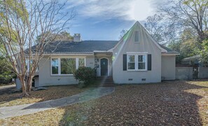 A single-story house with a gabled roof, a front entrance with a door, and a small porch area. - Stone Pool House - Sleeps 8 (Columbus)