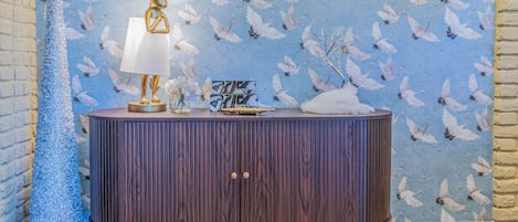 A room with a patterned wallpaper, a wooden cabinet, and a patterned rug.
