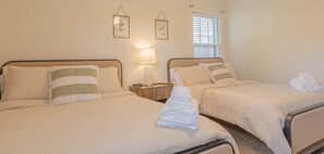 Ein Hotelzimmer mit zwei Betten, einem Nachttisch, einer Lampe und einem Fenster mit Jalousien.