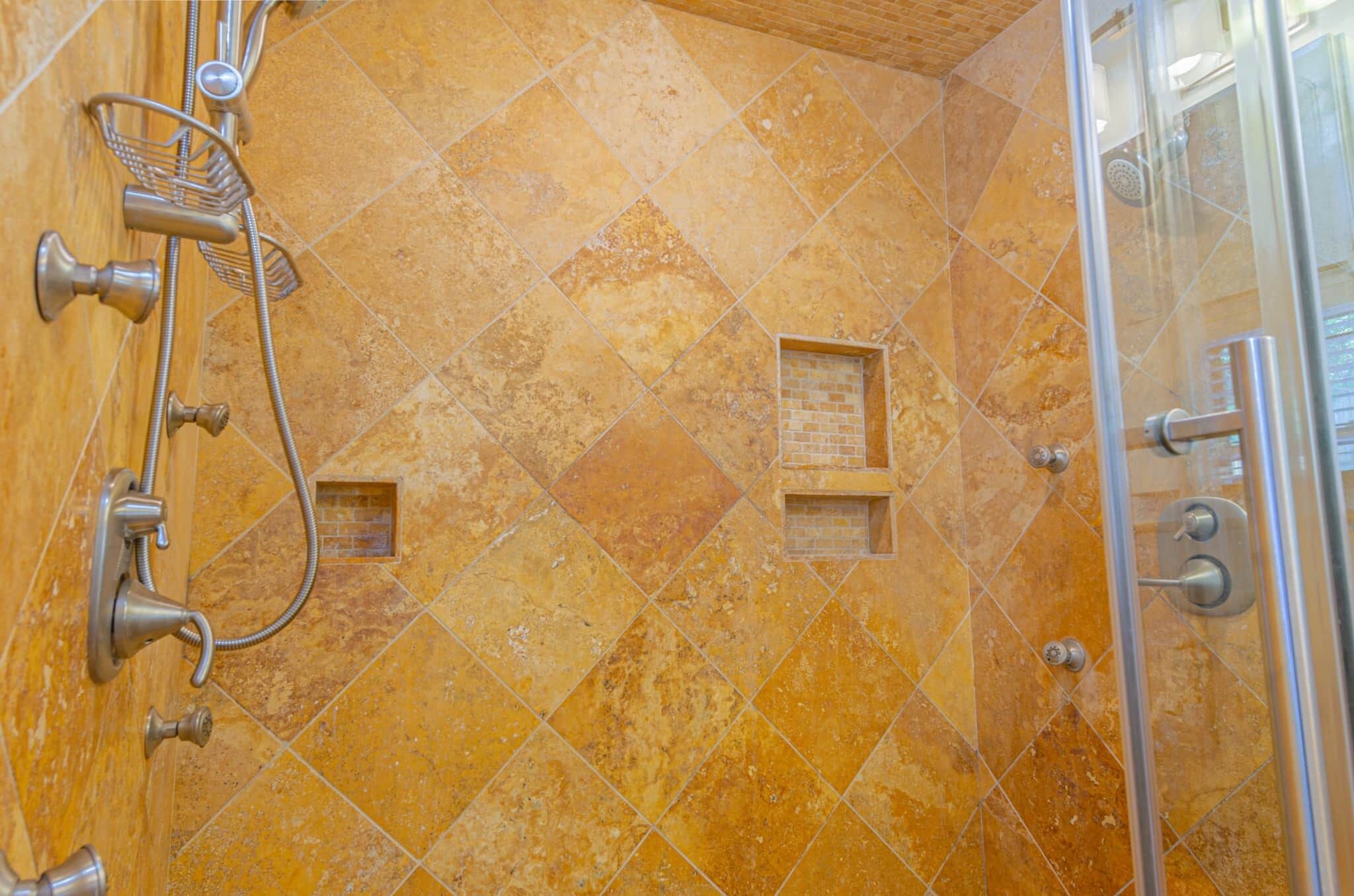 A shower area with a tiled wall, a glass door, and a showerhead.