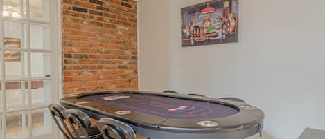 Un tavolo da poker con sedie, un muro in mattoni e un quadro appeso.
