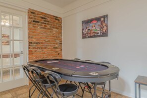 A poker table with chairs, a brick wall, and a painting on the wall. - Fort Benning Pool & Game Room Home - Sleeps 8 (Columbus)