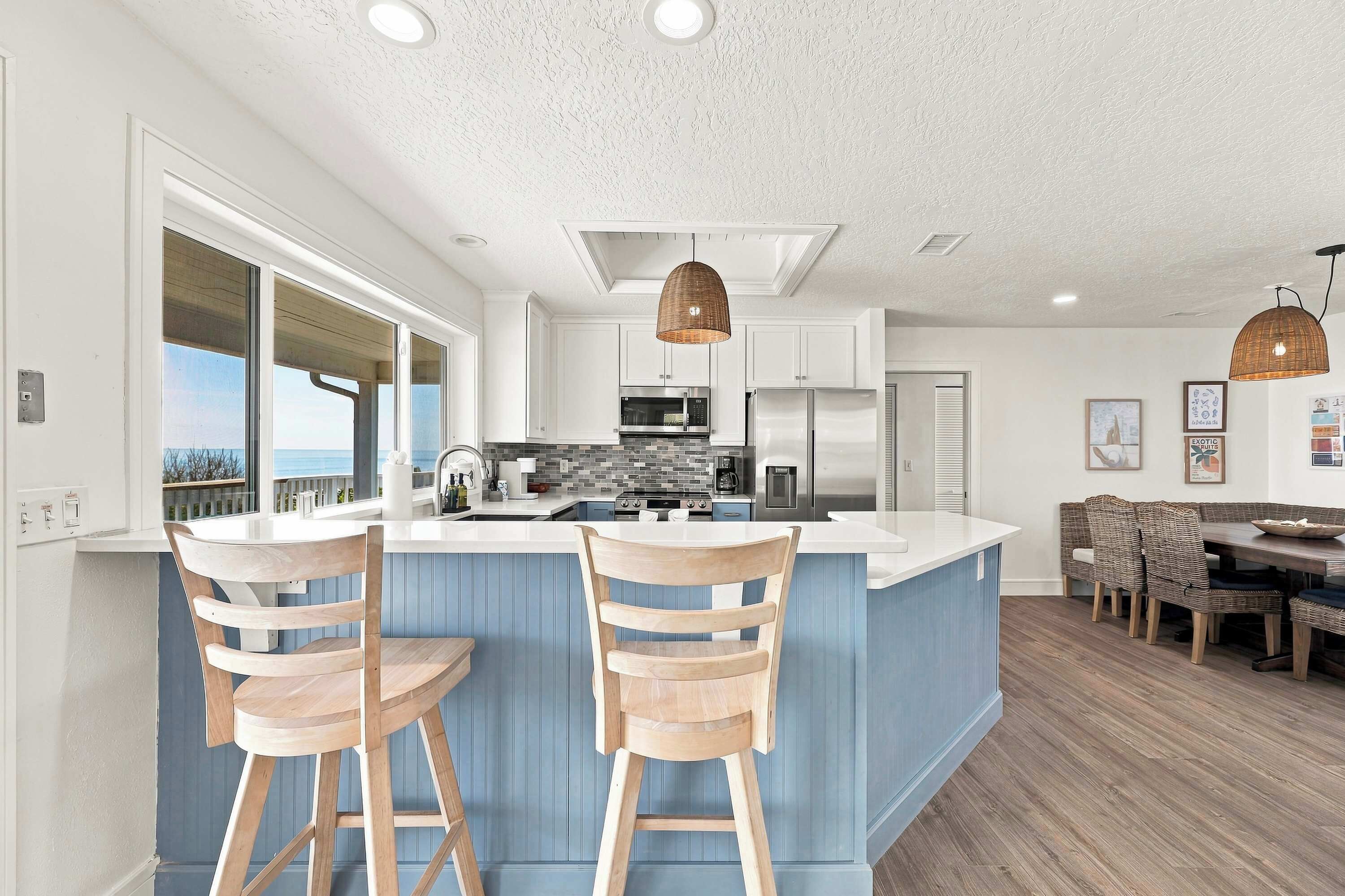 Una cocina moderna con una isla central, taburetes de bar y un comedor con vistas.