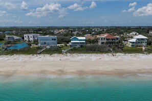 A coastal residential area with beachfront properties, including houses with balconies and a beach in the foreground. - 51 Steps: Beach House w/ Private Beach Access & Deck (Melbourne Beach)