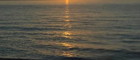 A sunset over a calm sea with a clear horizon.