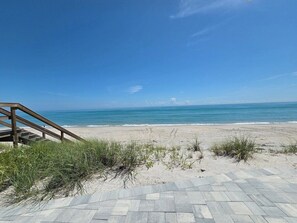 A paved walkway leading to a beach with a wooden staircase on the left. - Ocean Whispers at Tuscany Sun: Beach Studio (Melbourne Beach)