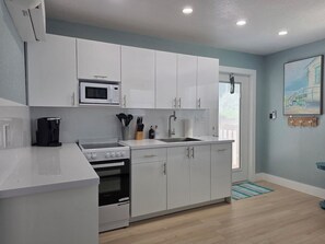 Una cocina moderna con armarios blancos, un microondas, una estufa y un fregadero.