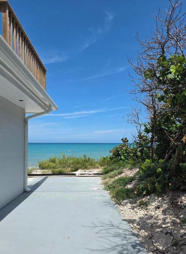 A pathway leading to a beachfront property with a clear view of the ocean. - Ocean Whispers at Tuscany Sun: Beach Studio (Melbourne Beach)