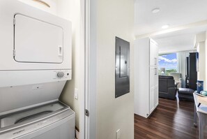 A laundry area with a washer and dryer, a doorbell, and a view of a balcony with a dining area. - Sandcastle Condominium Unit 109 (Port Aransas)