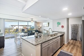 Una cocina moderna con una isla grande, un comedor con vistas y una sala de estar con sofá y sillones.