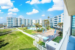 A hotel with multiple floors, a swimming pool, and outdoor seating areas. - Sandcastle Condominiums Unit 209 (Port Aransas)