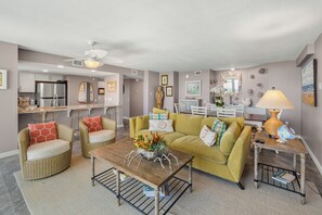 A modern living room with a sofa, chairs, a coffee table, and a dining area. - Sandcastle Condominiums 321 (Port Aransas)