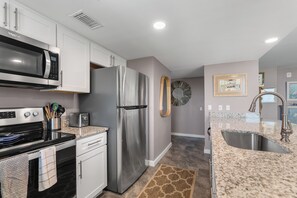 A modern kitchen with stainless steel appliances, a granite countertop, and a built-in oven. - Sandcastle Condominiums 321 (Port Aransas)