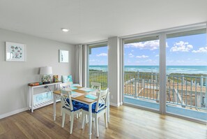 Een eetruimte met uitzicht op de oceaan en een balkon met een hekwerk.