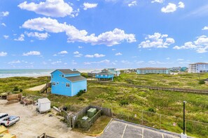 A coastal area with a blue house, a beach, and a row of buildings. - Sandcastle Condominiums 338 (Port Aransas)