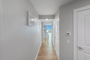 Ein Flur mit Holzboden, weißen Wänden und einer Tür auf der rechten Seite.