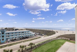 A beachfront hotel with multiple floors, a parking lot, and a view of the beach and ocean. - Sandcastle Condominiums 408 (Port Aransas)