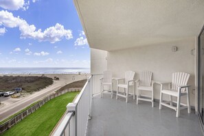 A balcony with white Adirondack chairs overlooking a beach. - Sandcastle Condominiums 408 (Port Aransas)
