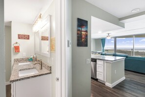 A modern kitchen with a granite countertop, a dishwasher, and a view of the ocean. - Sandcastle Condominiums 408 (Port Aransas)