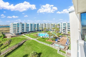 Ein Hotel mit mehreren Stockwerken, einem Schwimmbad und einem eingezäunten Rasen.