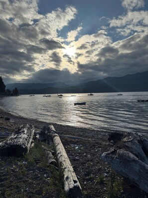 A lakeside view with boats, a wooden log, and distant mountains. - Beachfront Getaway on Hood Canal (Seabeck)