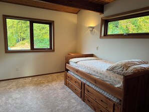 A bedroom with a bunk bed, two windows with views of greenery, a wall-mounted light, and a carpeted floor. - Beachfront Getaway on Hood Canal (Seabeck)