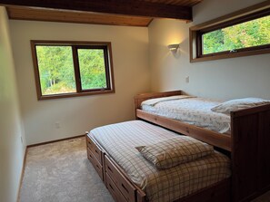 A bedroom with a bunk bed, a window with a view of trees, and a wall-mounted light fixture. - Beachfront Getaway on Hood Canal (Seabeck)
