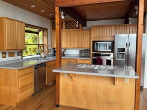 A modern kitchen with wooden cabinets, stainless steel appliances, and a granite countertop. - Beachfront Getaway on Hood Canal (Seabeck)