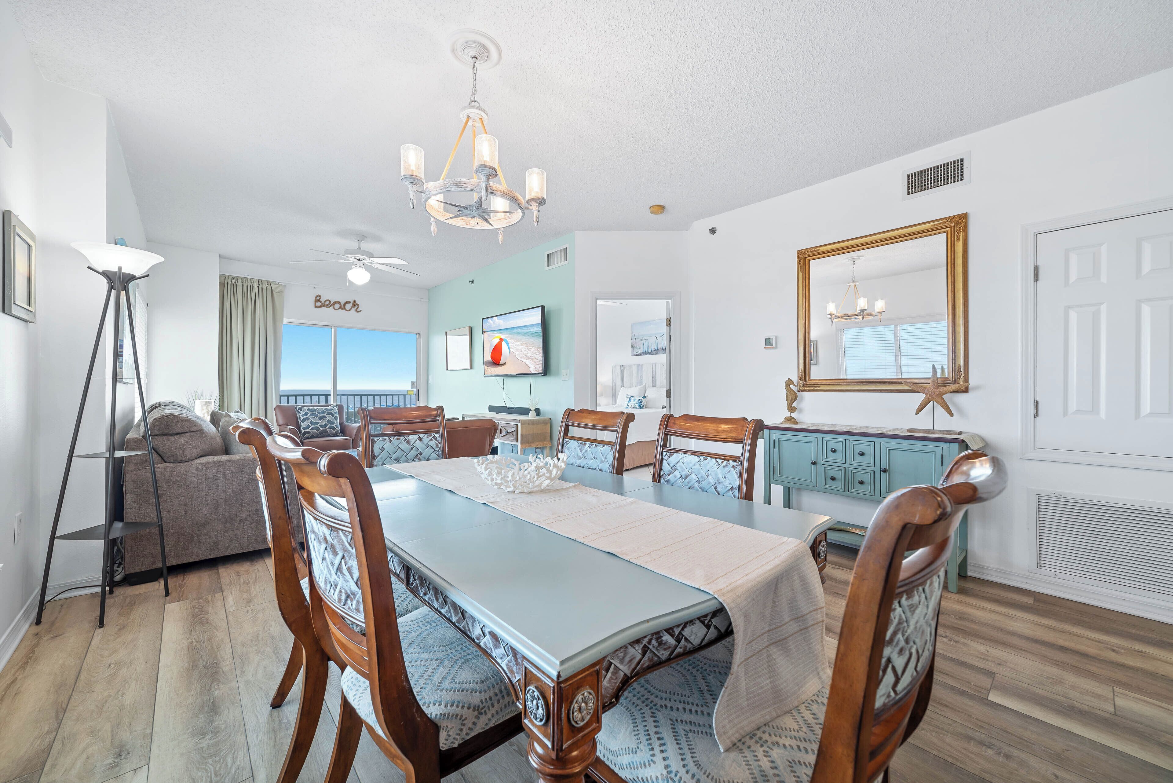 A dining area with a long table, wooden chairs, and a chandelier.