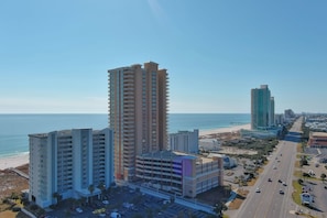 Ein Hochhaus-Hotel mit mehreren Etagen, einem Parkplatz und Blick auf Strand und Meer.