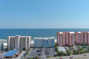 Ein Hotel direkt am Strand mit mehreren Gebäuden, einem Parkplatz und Blick auf den Ozean.