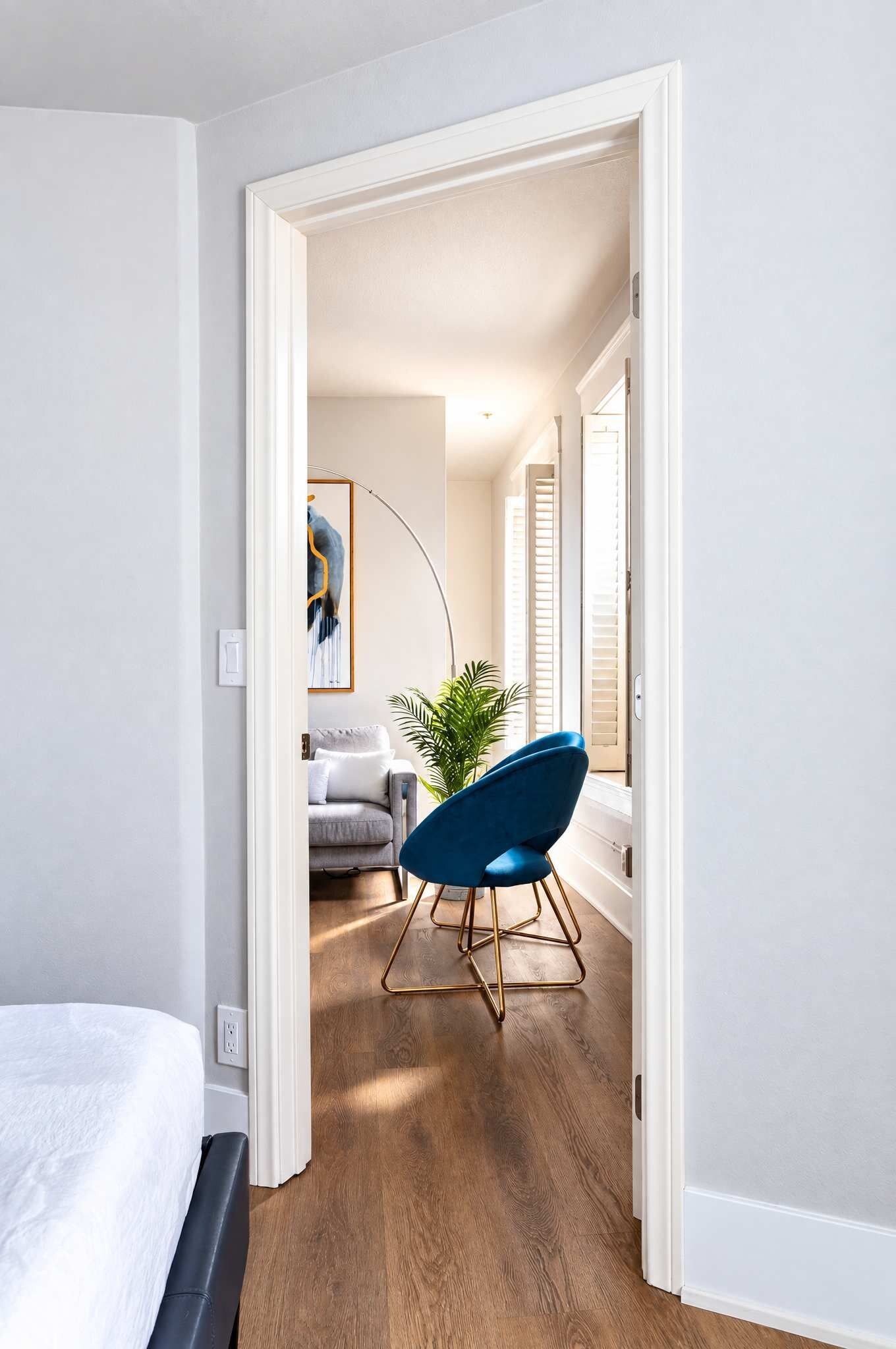 Un pasillo con una silla azul, un sofá gris y una planta.