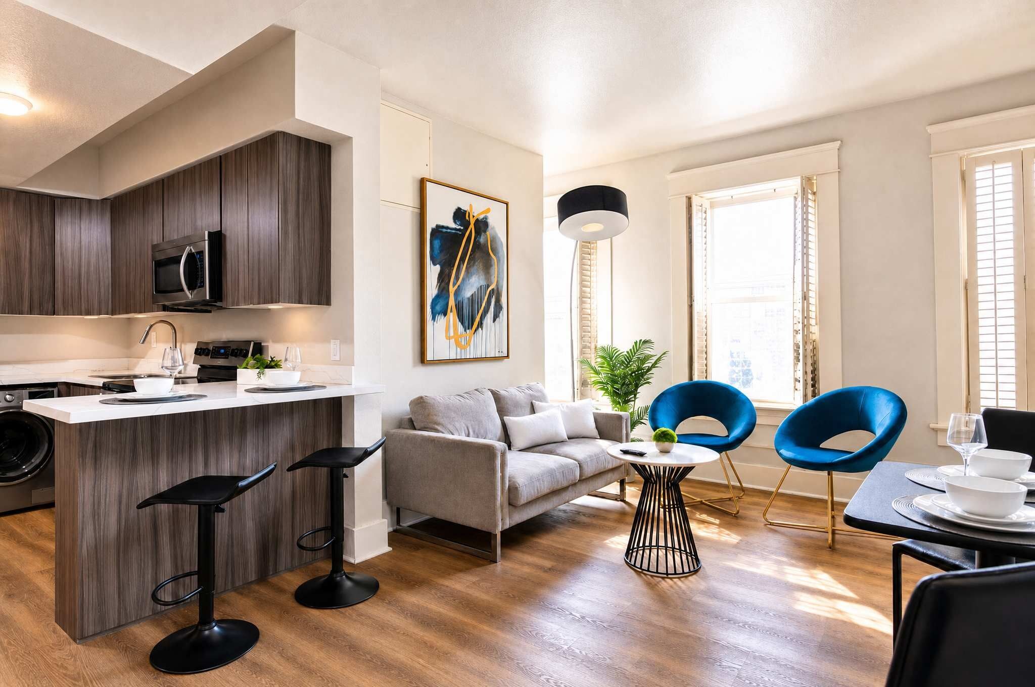 Eine moderne Küche mit Kochinsel, Barhocker, einer Couch und einem Essbereich mit blauen Stühlen.