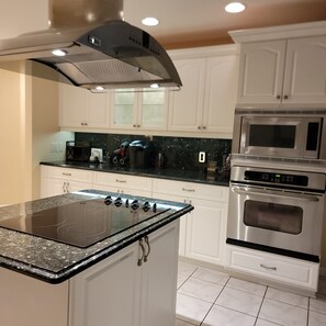 A kitchen with white cabinets, a black countertop, a stove, and a microwave. - Waterfront 3 BR / 3 bath home w/ heated pool in Punta Gorda Isles. Sleeps 8. (Punta Gorda)