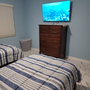 A bedroom with two beds, a dresser, a television on the wall, and a trash bin. - Waterfront 3 BR / 3 bath home w/ heated pool in Punta Gorda Isles. Sleeps 8. (Punta Gorda)