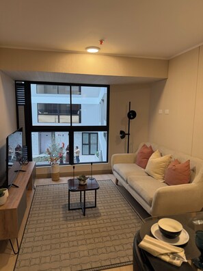 A modern living room with a large window, a sofa, a coffee table, and a TV. - Vrbo Property (Jesús María)