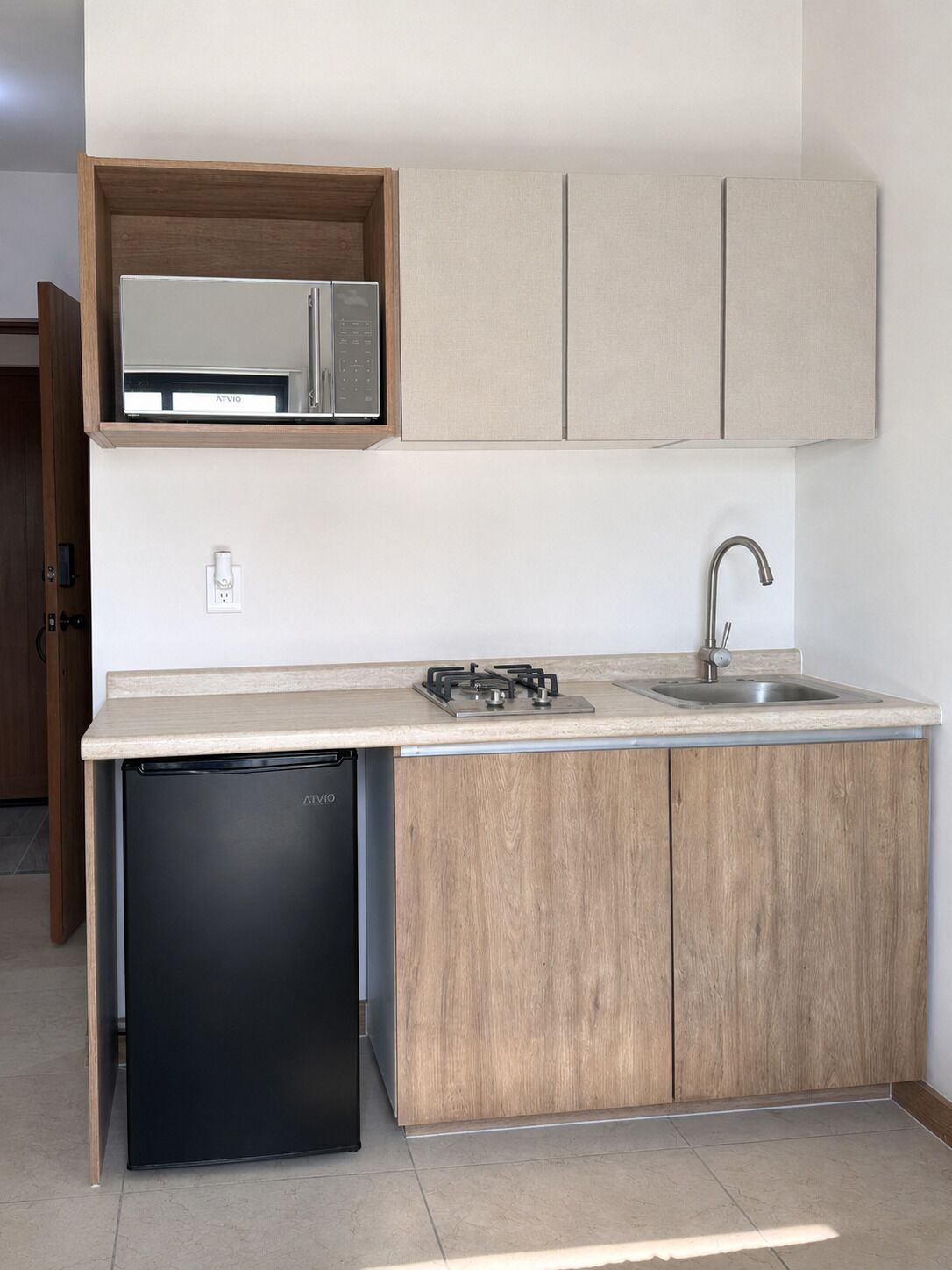 Cozinha compacta equipada com lava-louças embutida, micro-ondas, pia com torneira moderna e armários de madeira.