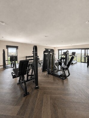 A spacious gym with various exercise equipment, large windows, and a herringbone wood floor. - New Studio · Rooftop · Historic Center of GDL (guadalajara)
