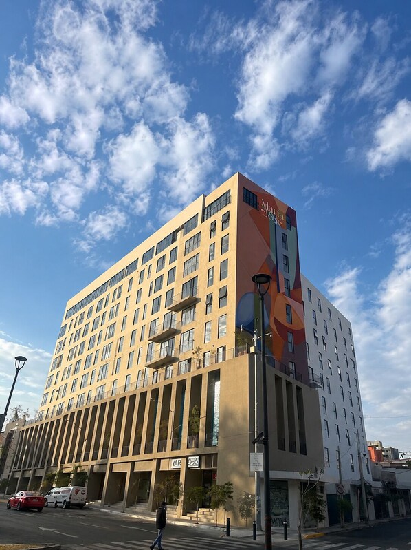Een hotel met meerdere verdiepingen, modern van ontwerp, met een opvallende ingang en een groot bord.
