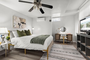 A modern bedroom with a bed, bedside table, lamp, and a TV on a stand.