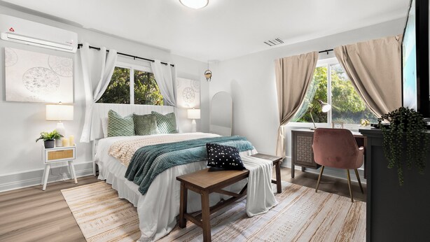 Ein Schlafzimmer mit einem Bett, Nachttischen, einem Schreibtisch und einem Stuhl.