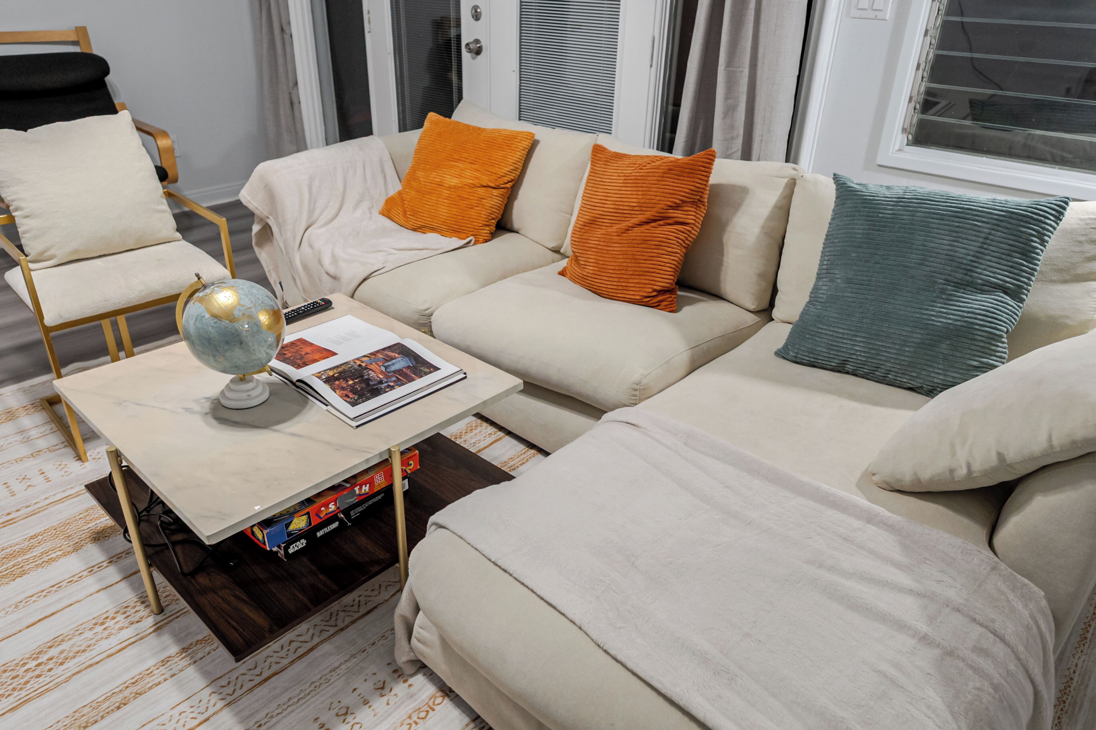 A living room with a sofa, armchairs, a coffee table with a globe, and a magazine.