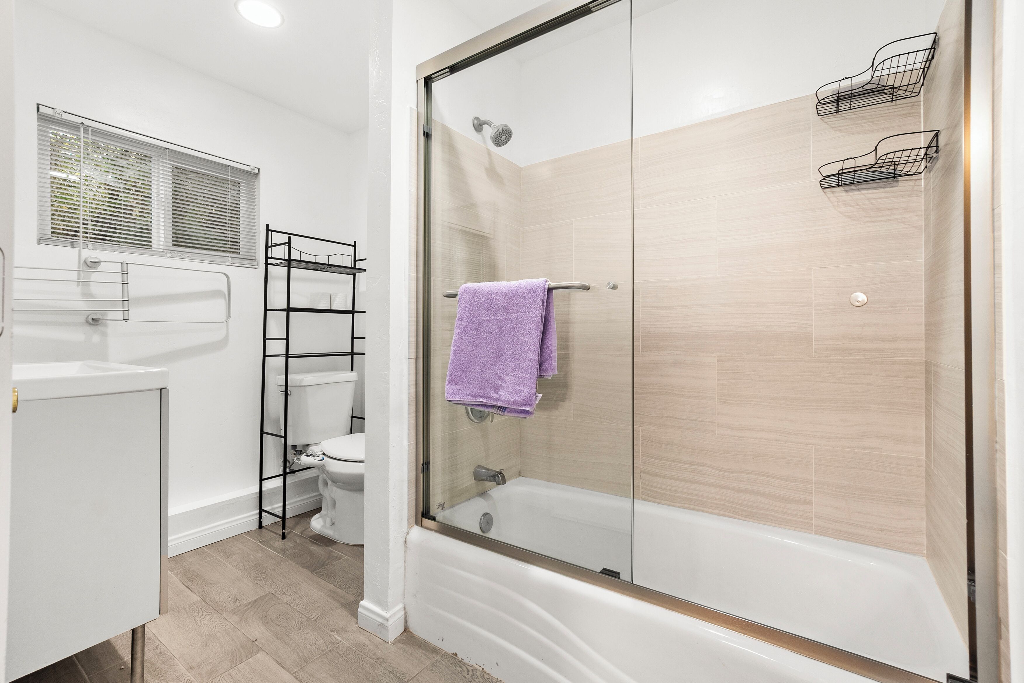 Un baño moderno con ducha de vidrio, lavamanos blanco y retrete.