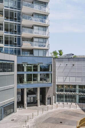 Un edifici modern de diversos pisos amb façana de vidre, zona d'aigües obertes i entrada visible amb el nom 'AQUA II'.
