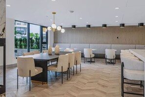 Una zona de menjador moderna amb una taula gran, molta cadira i il·luminació penjant.