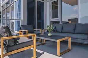 A modern outdoor seating area with sofas and chairs, a coffee table, and a potted plant. - Raindance 2BR+2BA | Central DT | Pet-friendly (Kelowna)