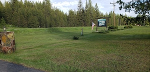 A grassy area with a sign for 'Swan River Lodge' and an American flag. - Charming 1-bedroom condo in peaceful Condon perfect for relaxing getaway (Condon)